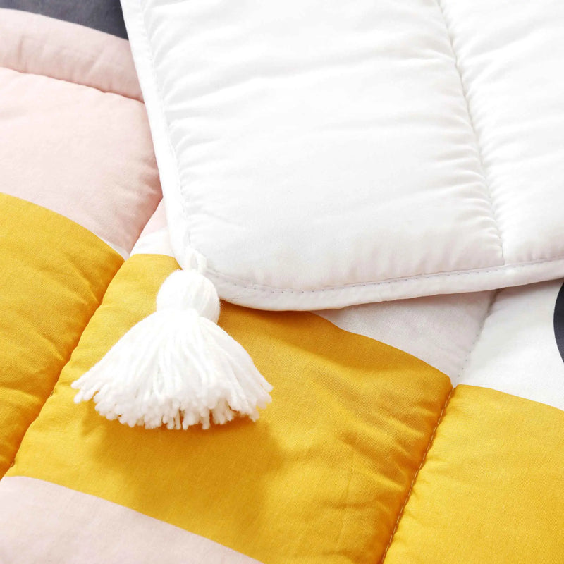 Close-up of a white tassel on a yellow and pink blanket