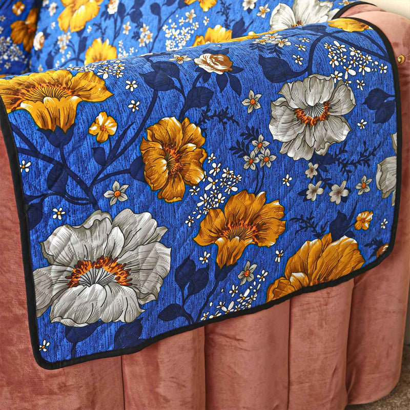 Close-up of blue floral sofa cover showing vivid orange and gray flowers and dark blue stems.