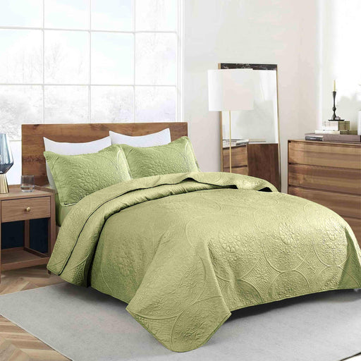 Close-up of green quilted bedding with floral pattern and stitching
