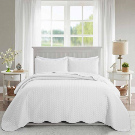A bed with a white quilted blanket and two nightstands.